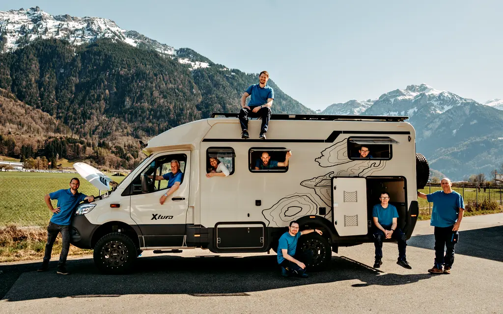 Das Team von Camptech Lüthi vor den Alpen mit einem umgebauten Camper